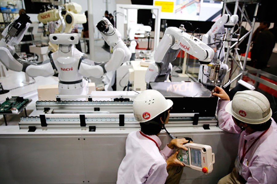 Staff programme a robot arm by Nachi Robotic Systems at the International Robot Exhibition in Tokyo, Japan on December 2, 2015. - Reuters file photo