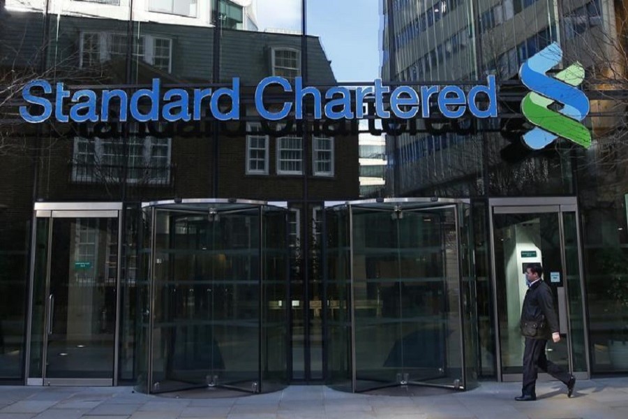 A man walks past the head office of Standard Chartered bank in the City of London February 27, 2015. Reuters/Files