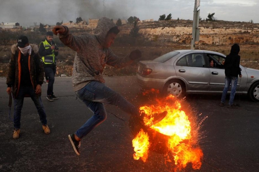 A Palestinian kicks a burning tyre during clashes with Israeli troops at a protest near the West Bank city of Ramallah December 10, 2017. Reuters