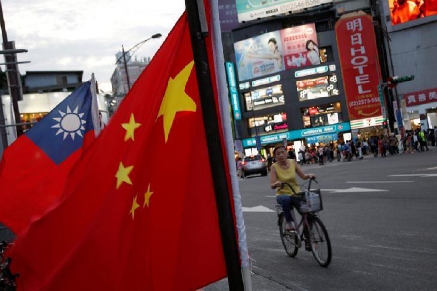 A woman rides a bike past Taiwan and China national flags during a pro-China rally in Taipei, Taiwan, May 14, 2016. Reuters/Files