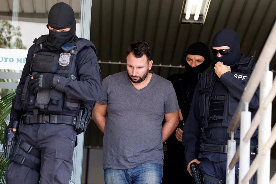 Spanish banker David Muino Suarez is escorted by federal police officers as he arrives to the Institute of Forensic Science in Curitiba, Brazil on November 28 laswt. - Reuters file photo