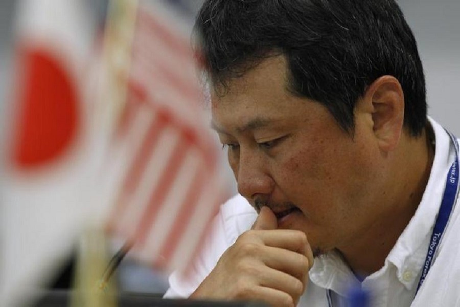 A foreign exchange broker rests his thumb on his lips as he is pictured near Japanese and American flags at a trading room in Tokyo October 26, 2011. Reuters/Files
