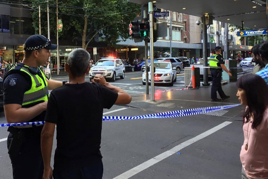 Police officers stand guard as members of the public stand behind police tape after the arrest of the driver of a vehicle that ploughed into pedestrians at a crowded intersection in central Melbourne, Australia on Thursday. - Reuters photo