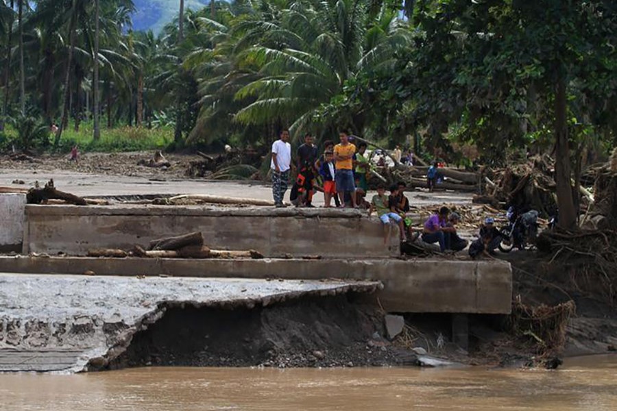 Residents stand on the edge of a destroyed bridge after flash floods in Salvador, Lanao del Norte in southern Philippines on Saturday. - Reuters photo