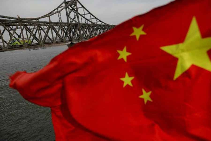 A Chinese flag is seen in front of the Friendship bridge over the Yalu River connecting the North Korean town of Sinuiju and Dandong in China's Liaoning Province on April 1, 2017. -- Reuters photo