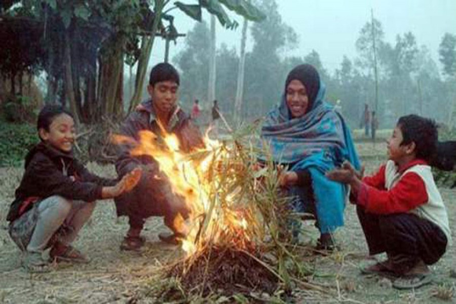 Cold-hit people sit by a fire to warm themselves at a slum of Rajshahi on Tuesday morning.  	— FE photo