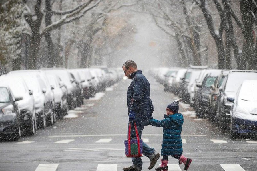 A man walks with a little girl as the snow falls in Central Park during a pre-winter storm in New York City, US, December 9, 2017. (REUTERS)