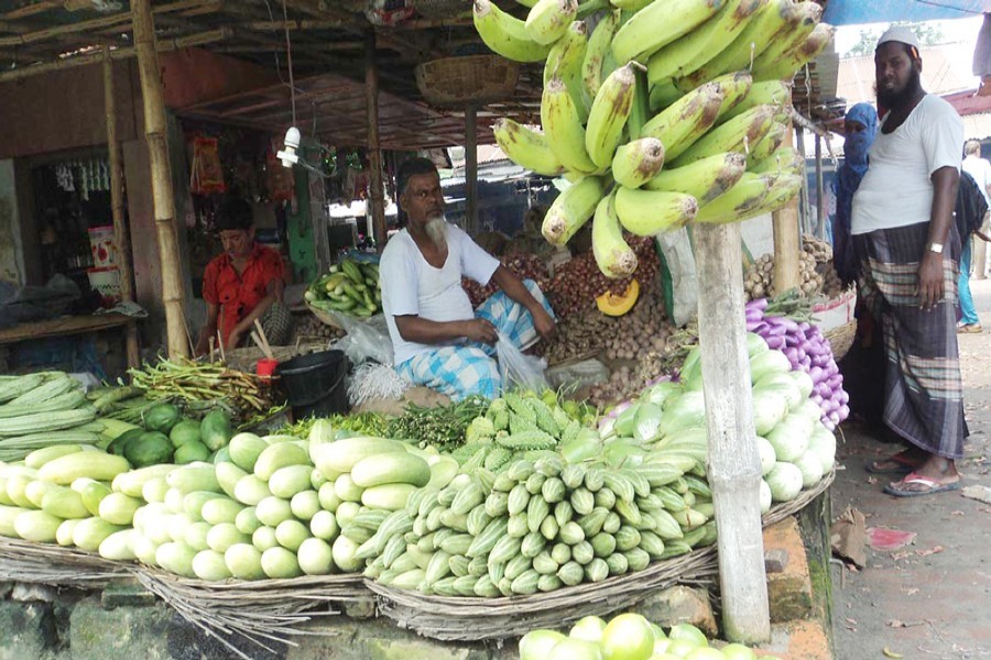 A vegetable seller waits for customers at his shop in a kitchen market of Bogra on Monday. — FE Photo