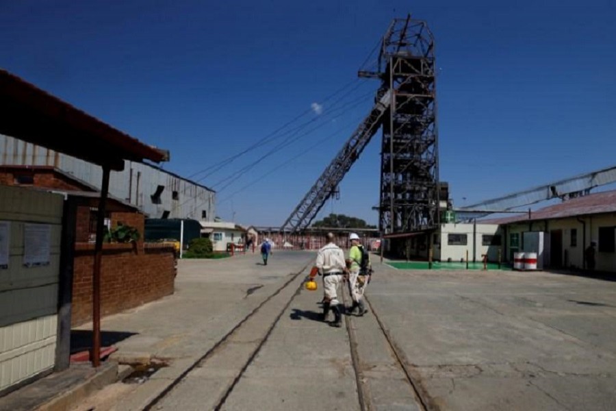 Mine workers walk past the pit head at Sibanye Gold's Masimthembe shaft in Westonaria, South Africa, April 3, 2017. Reuters