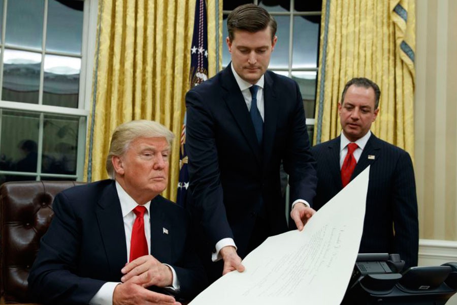 Then-White House Chief of Staff Reince Priebus, right, watches as White House Staff Secretary Rob Porter, centre, hands President Donald Trump a confirmation order in the Oval Office of the White House, in Washington, Jan 20, 2017. (AP)