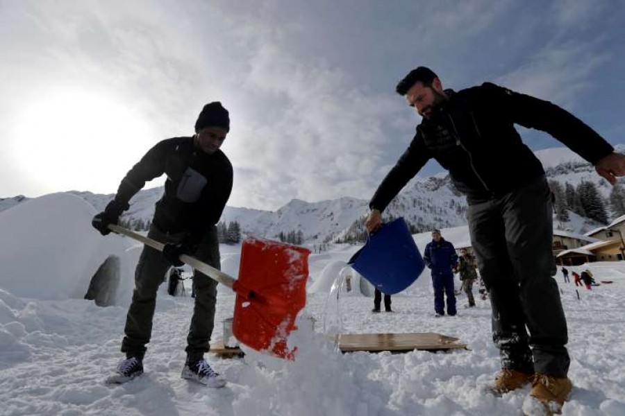 In this photo taken on Friday, Feb. 2, 2018, Moussa Sissoko, of Mali, left, helps build an igloo with Davide Midali, owner of an igloo village in San Simone di Valleve, near Bergamo, northern Italy. - AP