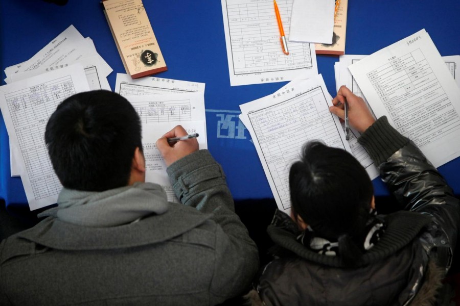 Job seekers fill in application forms during a job fair at Shanghai Stadium February 4, 2012. Reuters/File Photo