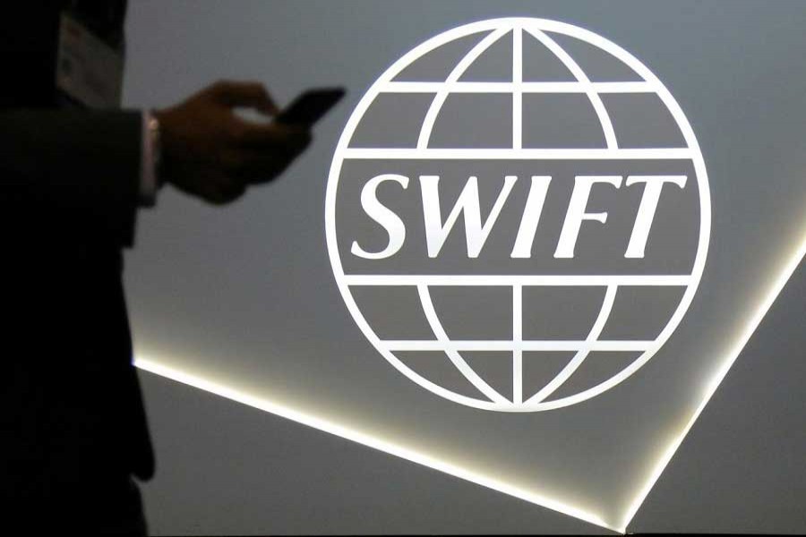 A man using a mobile phone passes the logo of global secure financial messaging services cooperative SWIFT at the SIBOS banking and financial conference in Toronto, Ontario, Canada October 19, 2017. Reuters/Files