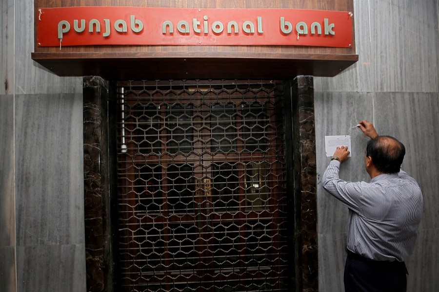 A man tries to remove a notice pasted on the wall of a Punjab National Bank branch after it was sealed by India's federal police in Mumbai, February 19, 2018. Reuters