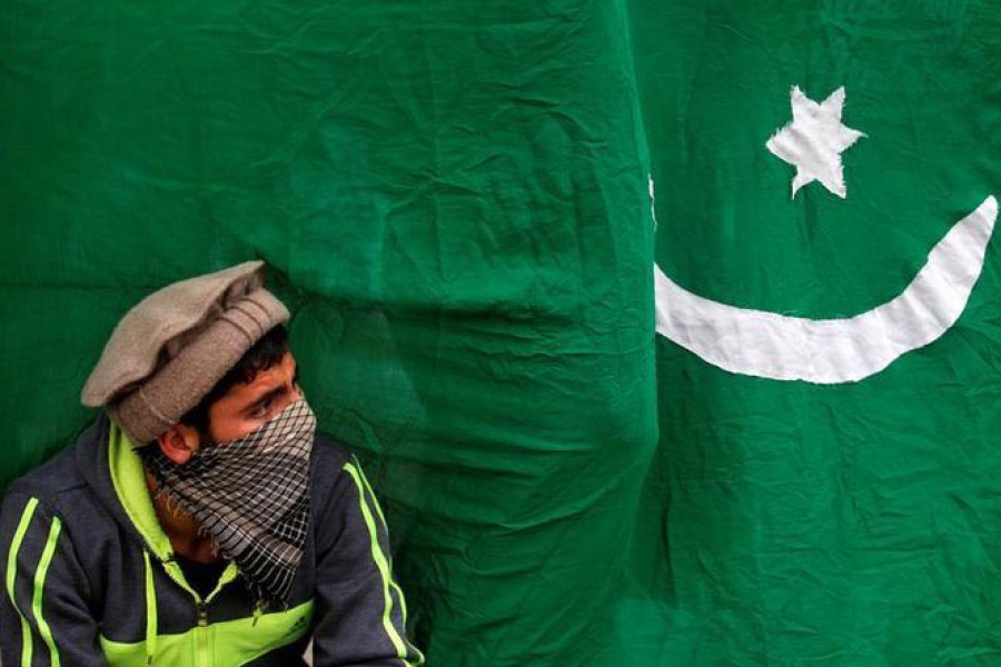 In this Reuters file photo, A masked protester sits next to a flag of Pakistan during an anti-Indian protest in Srinagar.