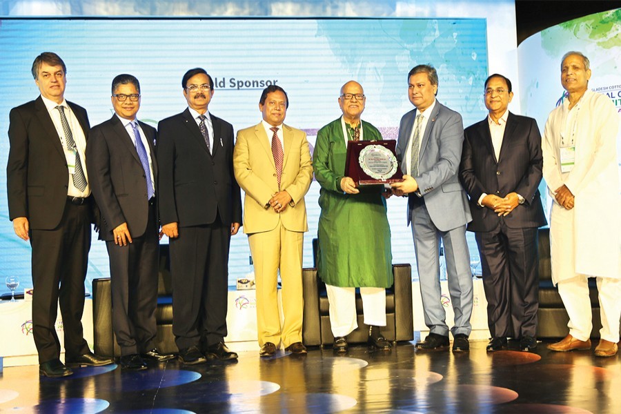Finance minister AMA Muhith receives crest at the Global Cotton Summit on Friday in Dhaka. President of the ICA Mirza Salman Ispahani (extreme left) seen, among others. — FE Photo