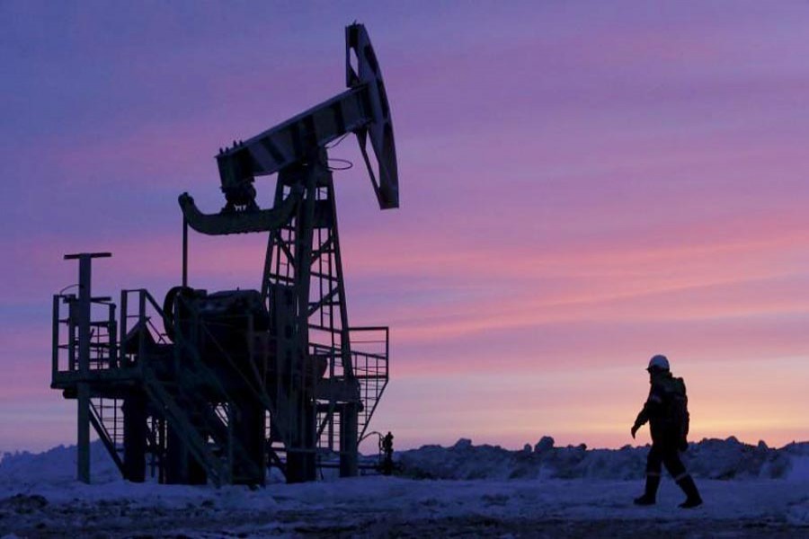 A worker walks past a pump jack on an oil field owned by Bashneft in Bashkortostan, Russia. 	— Reuters