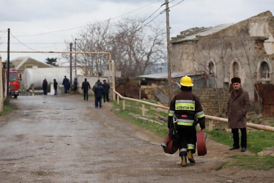 A firefighter carrying fire hoses walks near the scene of a fire which broke out in a drug rehabilitation centre in Baku, Azerbaijan on Friday. - Reuters photo