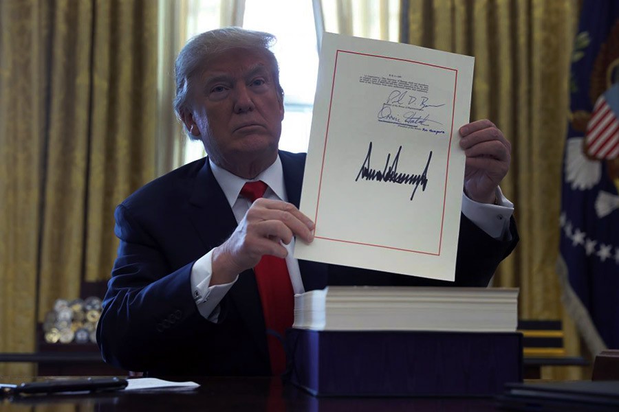 US President Donald Trump displays his signature after signing the $1.5 trillion tax overhaul plan in the Oval Office of the White House in Washington on December 22, 2017.       —Photo: Reuters