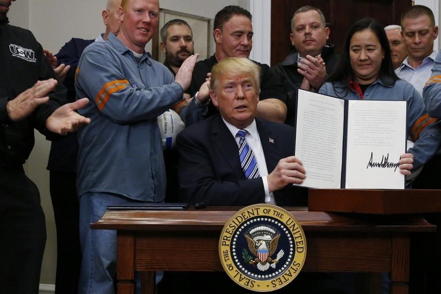 US President Donald Trump holds up a proclamation during a White House ceremony to establish tariffs on imports of steel and aluminium at the White House in Washington,March 8, 2018. Reuters