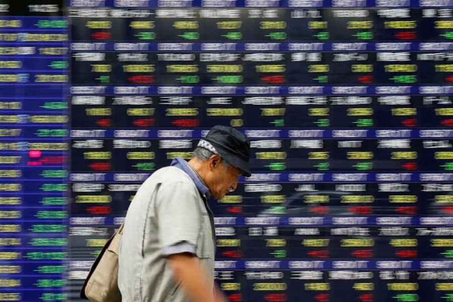 A man walks past an electronic stock quotation board outside a brokerage in Tokyo, Japan recently. Reuters/File Photo