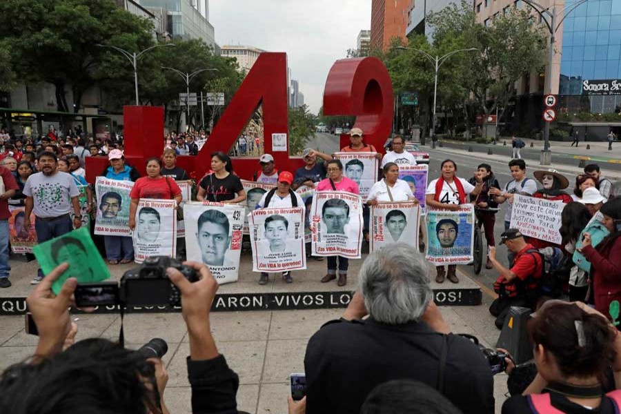 Relatives pose with images of some of the 43 missing Ayotzinapa College Raul Isidro Burgos students in front of a monument of the number 43, during a march to mark the 41st month since their disappearance in the state of Guerrero, in Mexico City, Mexico February 26, 2018. - Reuters