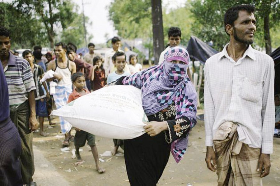 A Rohingya refugee woman carrying relief supplies to her makeshift shelter 	— Umer Aiman Khan/IPS