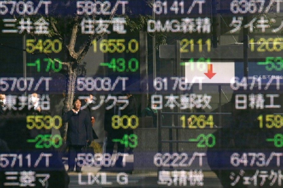 A man is reflected in an electronic stock quotation board outside a brokerage in Tokyo, Japan on Feb 9. Reuters/Files