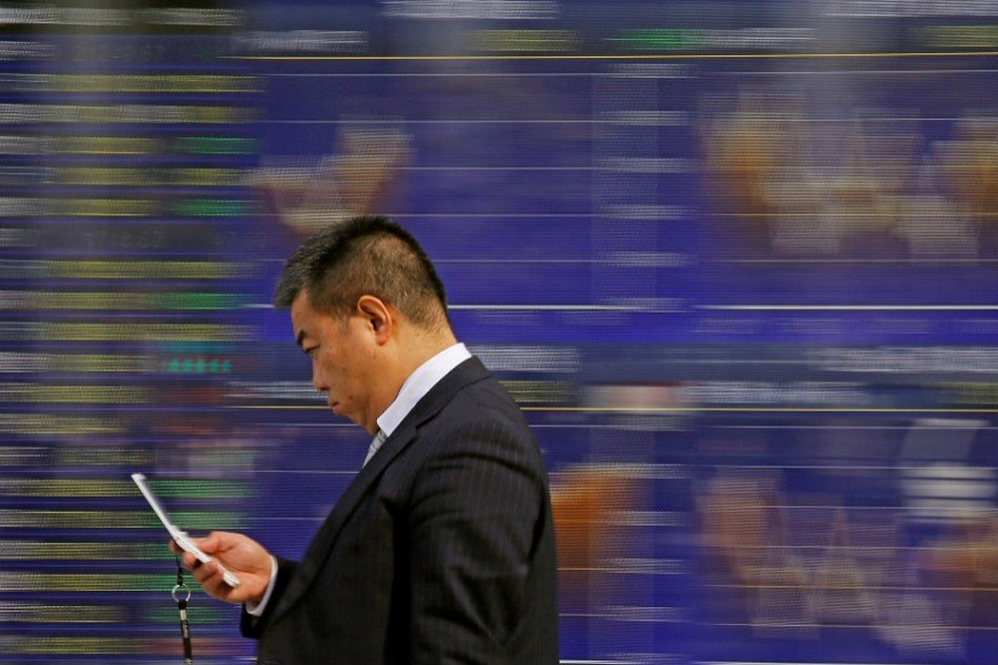 A man walks past an electronic stock quotation board outside a brokerage in Tokyo, Japan, February 9, 2018. Reuters/Files