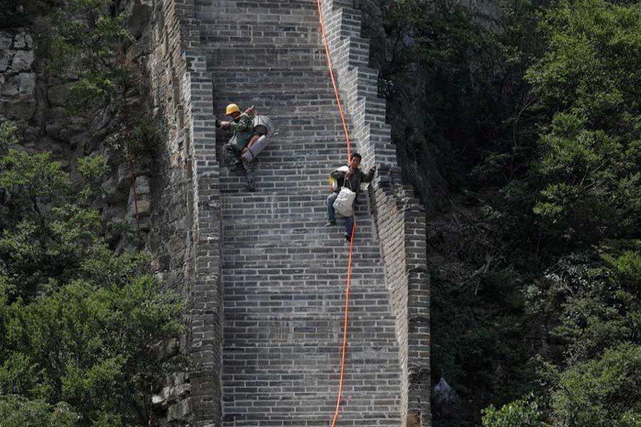 Workers carry their tools and belongings as they climb down the Jiankou section of the Great Wall, located in Huairou District, north of Beijing, China, June 7, 2017. Reuters/Files