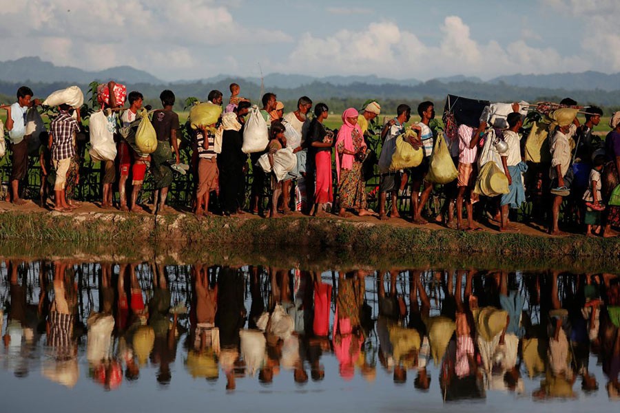 Rohingya refugees who fled from Myanmar wait to be let through by Bangladeshi border guards after crossing the border in Palang Khali, Bangladesh on October 9 last year - Reuters/File