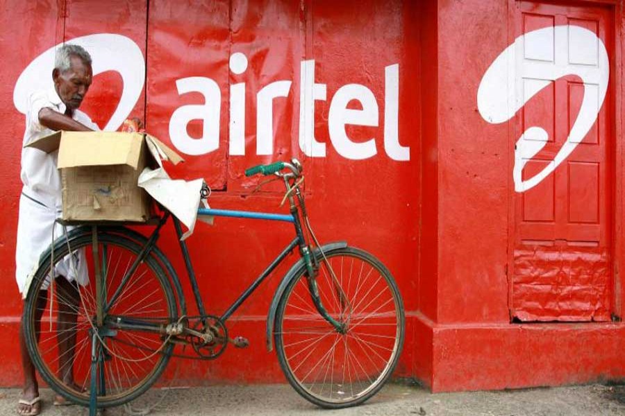 A man packs goods on the back of his bicycle as he stands next to the wall of a grocery shop painted with an advertisement for Bharti Airtel in the southern Indian city of Kochi May 5, 2011. Reuters/Files