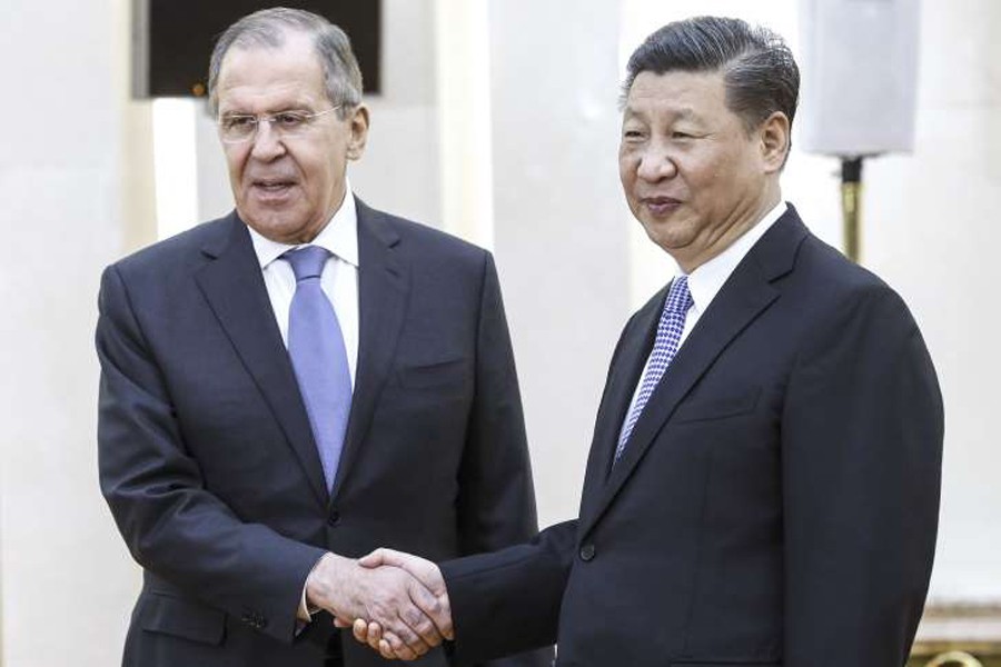 Russia's Foreign Minister Sergei Lavrov (L) and China's President Xi Jinping shaking hands ahead of a meeting of foreign ministers of the Shanghai Cooperation Organisation (SCO) Member States