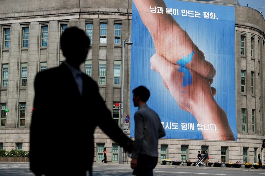 People walk past a large banner adorning the exterior of City Hall ahead of the upcoming summit between North and South Korea in Seoul, South Korea April 25, 2018. Reuters