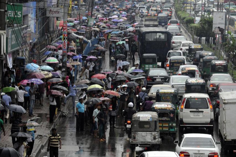 People wait for transportation in the rain in Dhaka. Xinhua File Photo