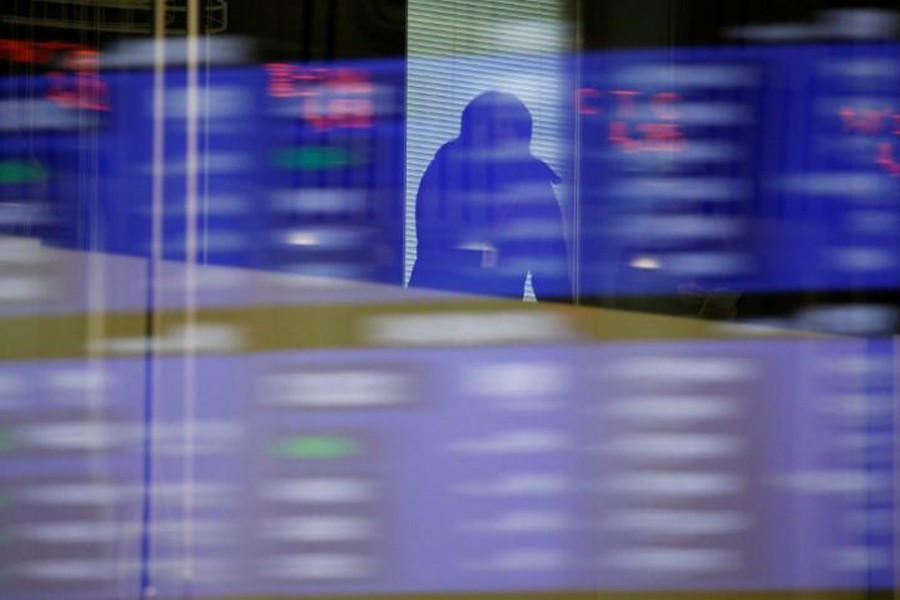 A visitor is seen as market prices are reflected in a glass window at the Tokyo Stock Exchange (TSE) in Tokyo, Japan, February 6, 2018. Reuters/File Photo