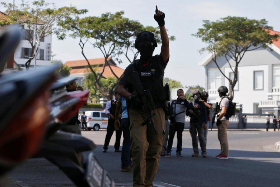 Anti-terror policemen stand guard following a bomb blast at police office in Surabaya, Indonesia on Monday