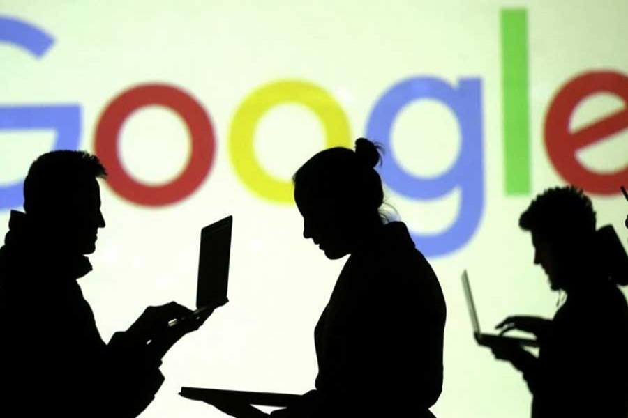 Silhouettes of laptop and mobile device users are seen next to a screen projection of Google logo in this picture illustration taken March 28, 2018. Reuters/File Photo