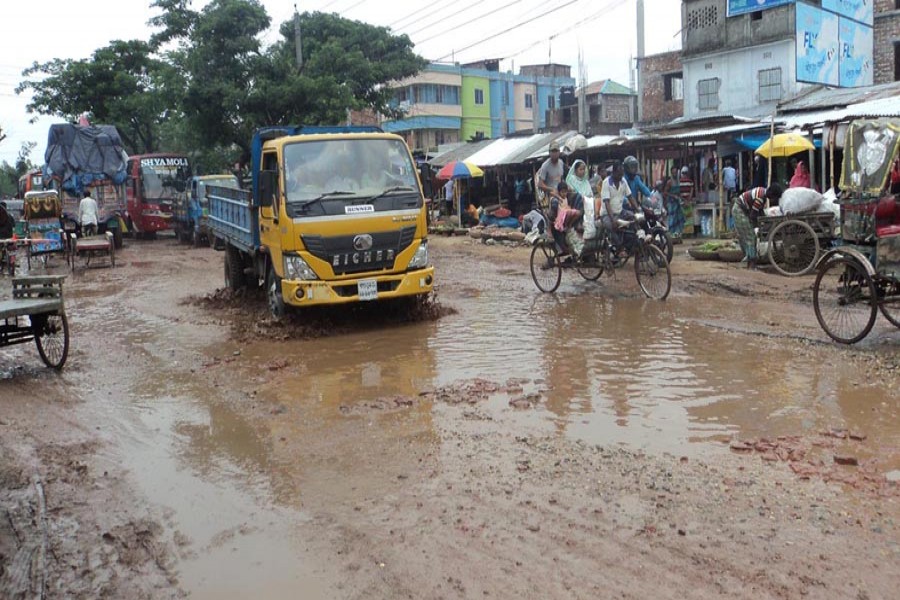 Vehicles plying the dilapidated Bogura-Naogaon road near Goderpara Bazar under Bogura Sadar on Saturday    	— FE Photo