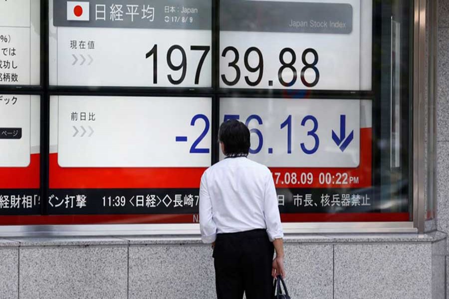 A man looks at an electronic board showing Japan's Nikkei average outside a brokerage at a business district in Tokyo, Japan, August 9, 2017. Reuters/Files