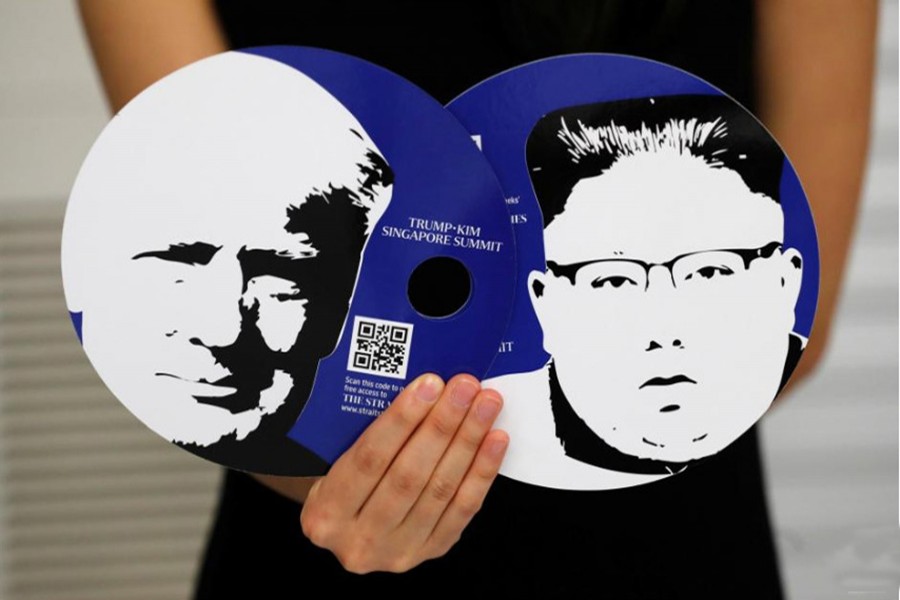 A worker of a media center for the summit between the U.S and North Korea shows fans featuring the images of U.S. President Donald Trump (L) and North Korean leader Kim Jong Un, which provided for journalists in a media kit at the media center in Singapore, June 10, 2018. REUTERS/Kim Kyung-Hoon