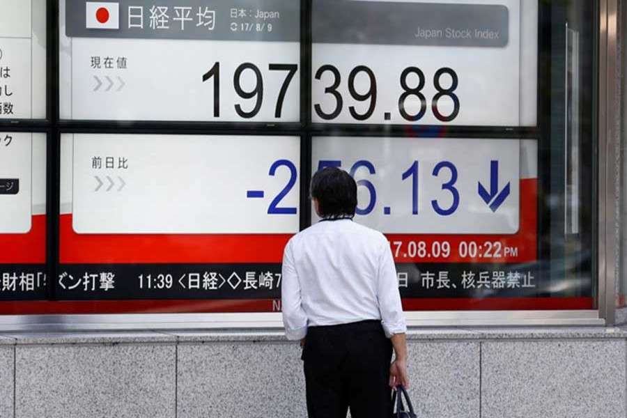 A man looks at an electronic board showing Japan's Nikkei average outside a brokerage at a business district in Tokyo, Japan August 9, 2017. Reuters/Files