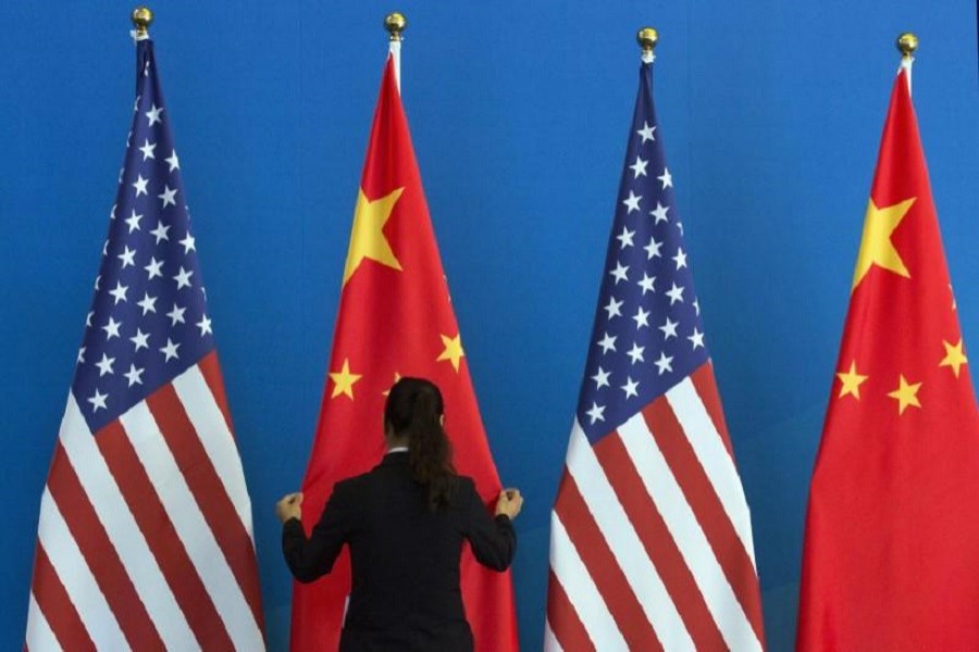 A Chinese woman adjusts a Chinese national flag next to US national flags before a Strategic Dialogue expanded meeting, part of the US-China Strategic and Economic Dialogue (S&ED) held at the Diaoyutai State Guesthouse in Beijing, July 10, 2014. Reuters/Files