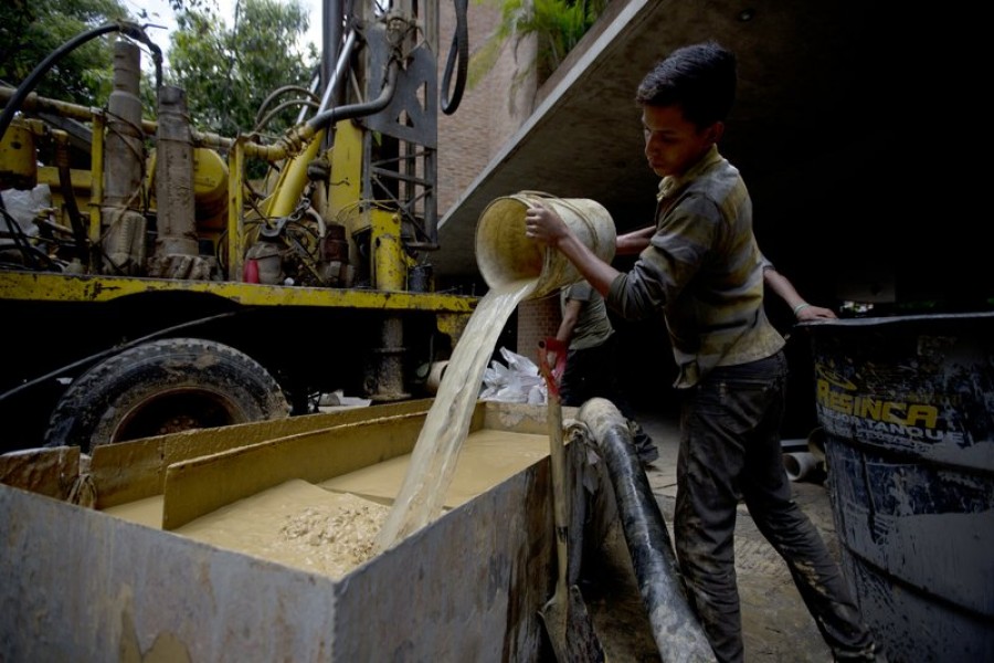 In this file photo, a worker clears the mud from a drill as a water well is put in at a luxury apartment complex in the Campo Alegre neighbourhood of Caracas, Venezuela. - AP photo