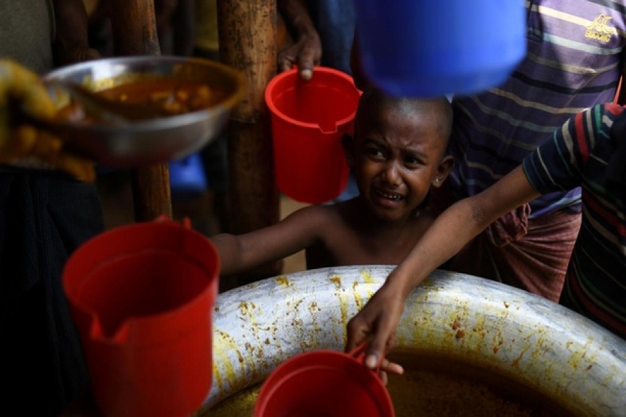 A Rohingya refugee child is handed food rations at Jamtoli refugee camp near Cox's Bazaar, Bangladesh, March 29, 2018. Reuters/Files