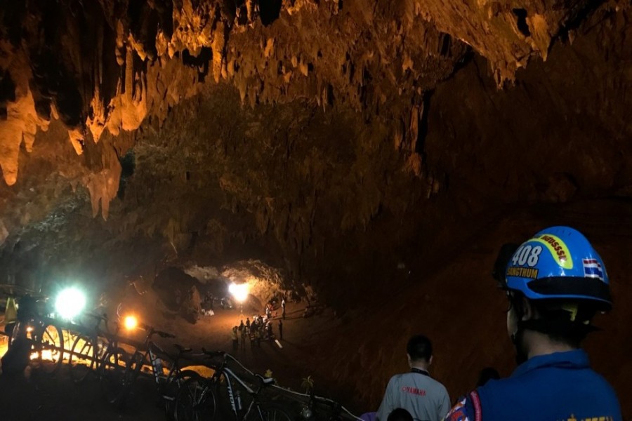 Soldiers and rescue workers walk past water pumped out of Tham Luang cave complex, where members of an under-16 football team and their coach have been found alive, in the northern province of Chiang Rai, Thailand, July 5, 2018. Reuters