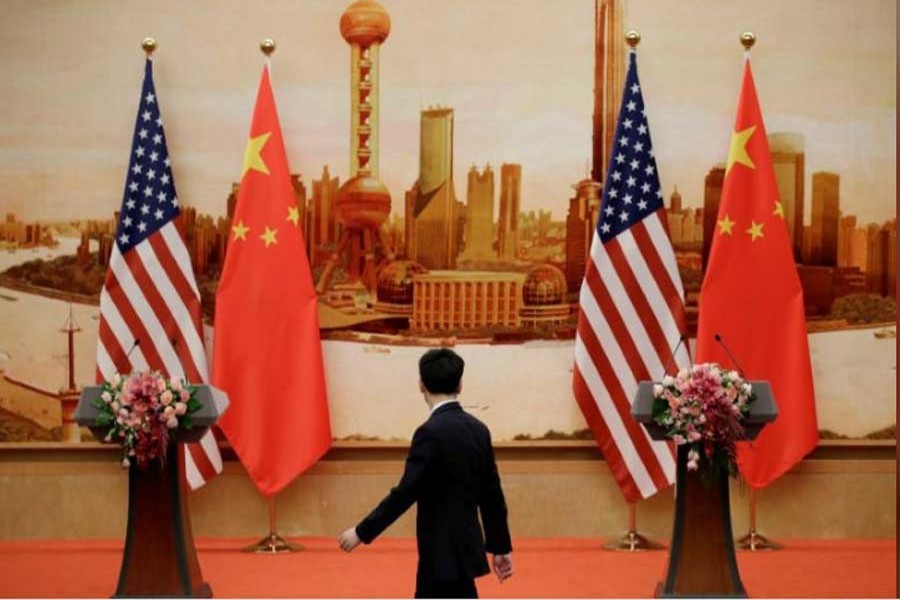 A staff member walks past US and Chinese flags placed for a joint news conference by US Secretary of State Mike Pompeo and Chinese Foreign Minister Wang Yi at the Great Hall of the People in Beijing, China, June 14, 2018. Reuters/Files