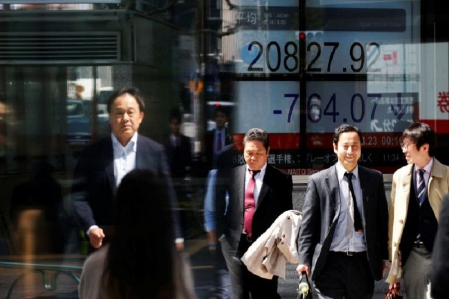 People walk past an electronic board showing Japan's Nikkei average outside a brokerage in Tokyo, Japan, March 23, 2018. Reuters/File Photo