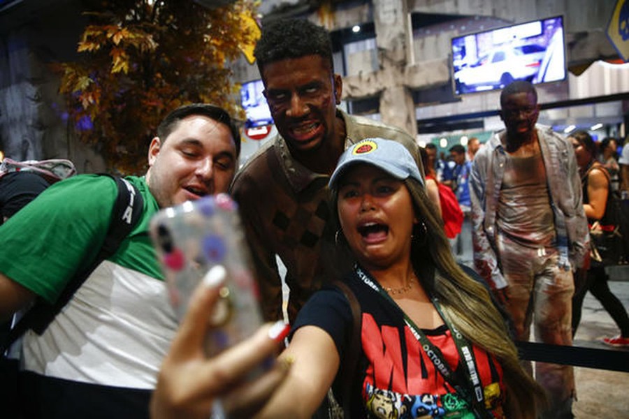 Tim Walker, 26, and Julia Homitano, 27, take selfies with zombies while waiting in line for "The Walking Dead" booth on Wednesday. Photo: Los Angeles Times