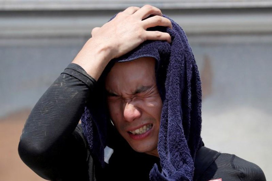 A volunteer, for recovery work, wiping his sweat as he takes a break in a heat wave at a flood affected area in Japan recently. -Reuters Photo